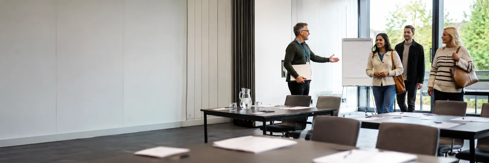 Facilitator welcoming attendees into a business support workshop with materials laid out