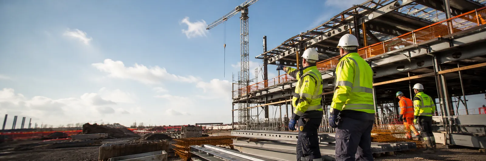 Workers walking toward a steel-frame construction